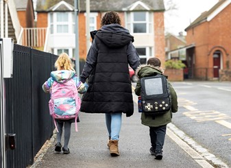 An adult and two children walk to school